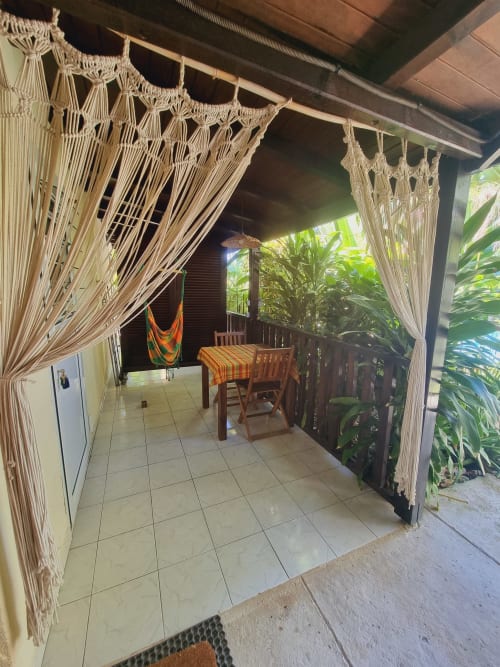 Covered patio with macramé curtains, dining table, and hammock at Gites Kaladja studio in Port-Louis, Guadeloupe