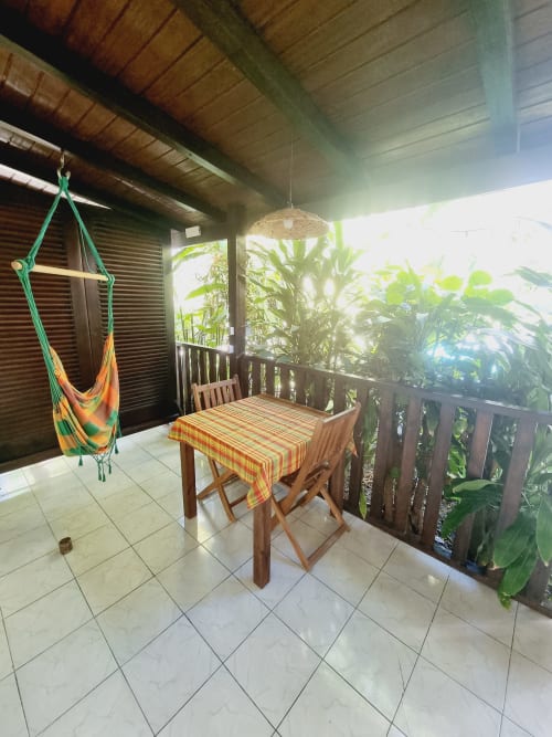 Covered outdoor patio at Gites Kaladja Port-Louis with dining table, colorful hammock, and tropical plants