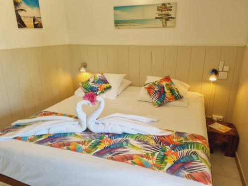 Colorful tropical studio bedroom at Gites Kaladja with twin beds, decorative towel swans, and vibrant patterned bedding in