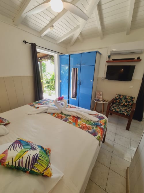 Bright studio bedroom at Gites Kaladja with two single beds, blue wardrobe, tropical decor, and garden view in Port-Louis,