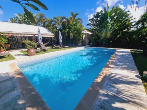 Bright rectangular swimming pool with wooden deck at Gites Kaladja BnB in Port-Louis, Guadeloupe, surrounded by tropical