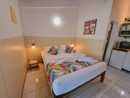 Toumblak studio bedroom at Gites Kaladja in Port-Louis with double bed, colorful decor, kitchenette, and bright lighting