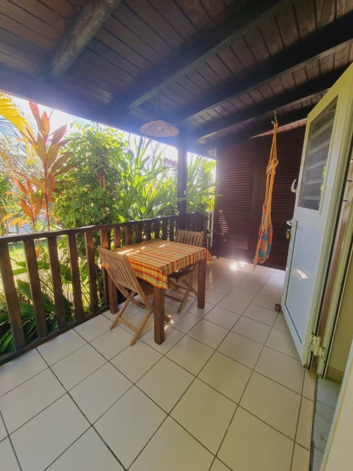 Covered patio with dining table and chairs overlooking lush garden at Gites Kaladja studio in Port-Louis, Guadeloupe