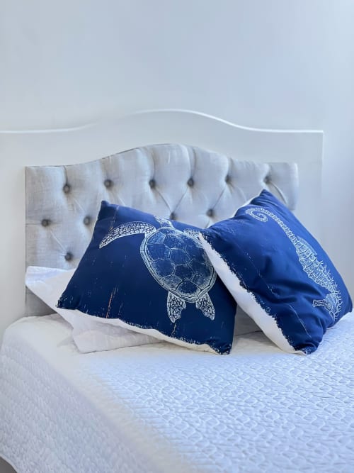 Cabecero tapizado blanco con almohadas de tortuga marina azul en el hotel Olamar Living de Santiago de Tolú