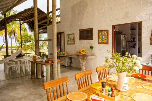 Área de comedor al aire libre de Olamar Living con sillas de madera, palmeras y vista costera en Santiago de Tolú, Colombia