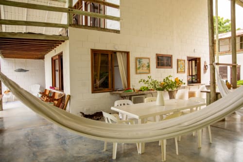 Patio de Olamar Living en Santiago de Tolú con hamaca, mesa de comedor y arquitectura de ladrillo blanco
