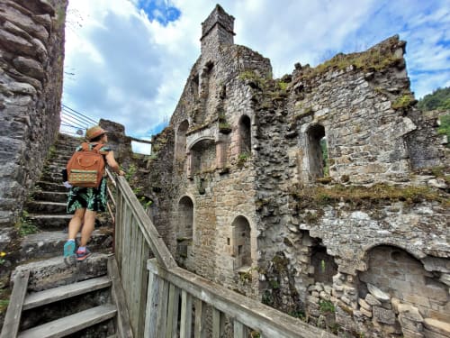 Randonneur explorant les ruines de pierre ancienne avec tour à Darazac, France. Ciel bleu, architecture médiévale couverte de mousse.