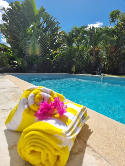 Toalla amarilla y blanca con flor rosa junto a la piscina en Gites Kaladja, Port-Louis Guadeloupe