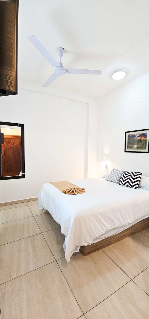 Clean Queen Size Room at La Familia Hotel in San Blas with ceiling fan, framed artwork, and comfortable bedding