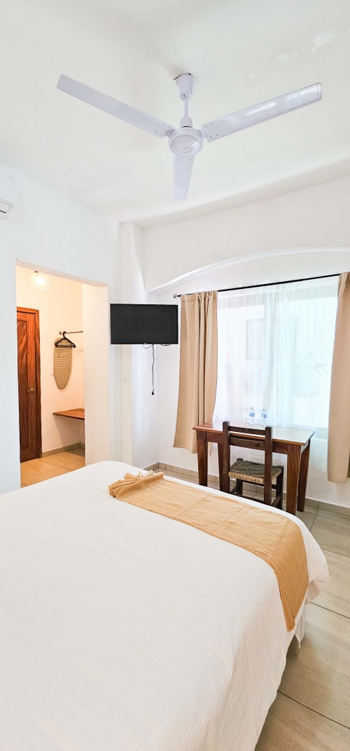 Queen size bedroom at La Familia Hotel in San Blas with white ceiling fan, flat-screen TV, and modern amenities