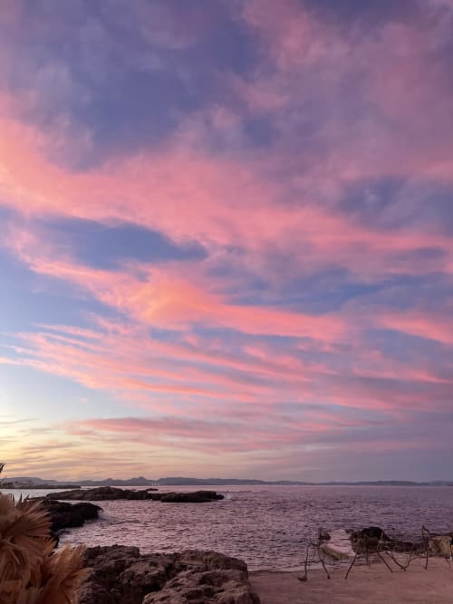 Puesta de sol sobre el mar Mediterráneo en Formentera Especial, La Savina con costa rocosa y tumbonas