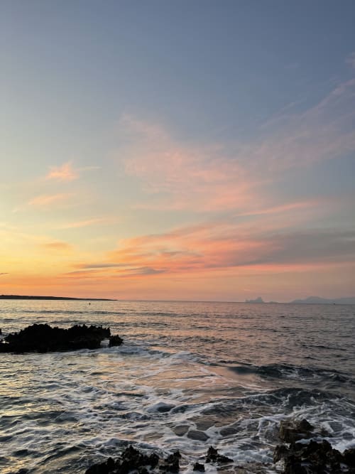 Atardecer sobre las aguas mediterráneas de Formentera, litoral rocoso con olas en La Savina