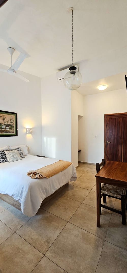 Queen Size Room at La Familia Hotel in San Blas, Nayarit with bed, ceiling fan, and pendant light