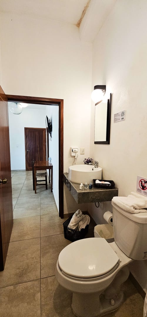 Bathroom in La Familia Hotel Queen Size Room, San Blas with toilet, round sink, mirror and entrance to bedroom