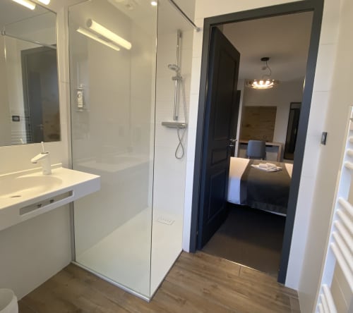 Salle de bains moderne de l'Hôtel Saint Roch avec douche à l'italienne, vasque blanche, miroir et sol en bois, Saint Ybard