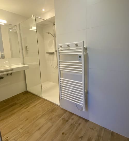 Salle de bains moderne à l'Hôtel Saint Roch avec douche vitrée, porte-serviettes chauffant et carrelage blanc