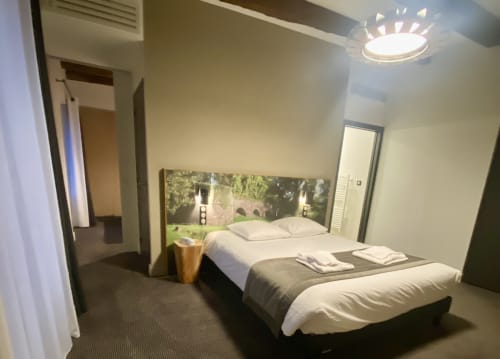 Chambre moderne à l'Hôtel Saint Roch à Saint Ybard avec lit queen-size, œuvre d'art paysagère en tête de lit, luminaire au plafond et salle de bain privée