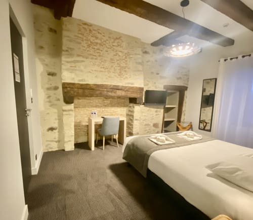 Chambre moderne de l'Hôtel Saint Roch avec lits jumeaux, foyer en brique, bureau et mobilier contemporain
