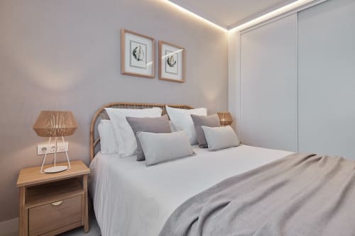 Habitación moderna en Wehost Costaluz de Puerto Santa María con ropa de cama blanca, mesilla de madera y decoración contemporánea
