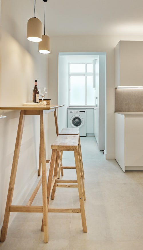 Cocina moderna con barra de madera, luces colgantes, comedor y lavadora en apartamento de Puerto Santa María