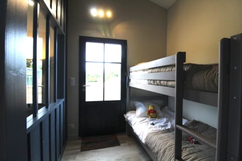 Chambre avec lits superposés au gîte Moulin d'Angibaud à La Flotte, encadres en bois foncé et porte donnant sur le jardin
