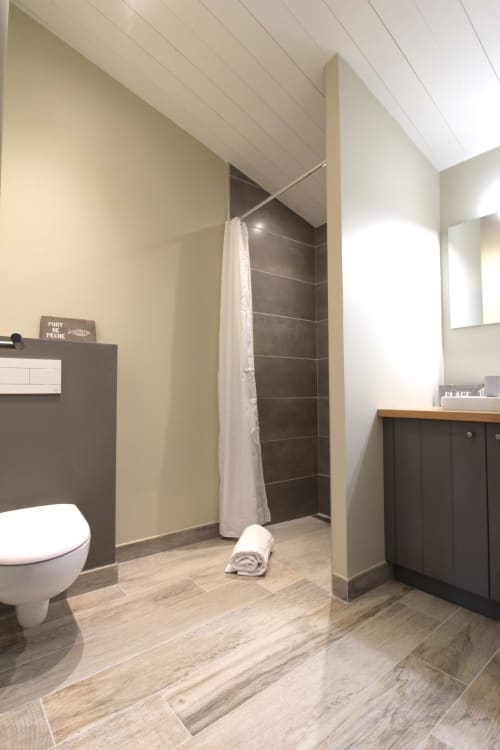 Salle de bain moderne du gîte Bleu au Moulin d'Angibaud, La Flotte, avec douche en carrelage foncé, vasque, toilettes et revêtement effet bois