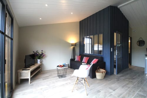 Salon du gîte Bleu au Moulin d'Angibaud, La Flotte avec mur d'accent noir moderne, TV, canapé et vue sur le jardin