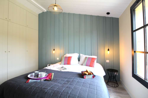 Chambre moderne au gîte Moulin d'Angibaud avec lits jumeaux, mur accent turquoise, luminaires suspendus et vue jardin