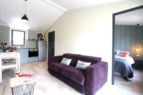 Séjour moderne du Moulin d'Angibaud avec canapé violet, cuisine et vue sur chambre à La Flotte