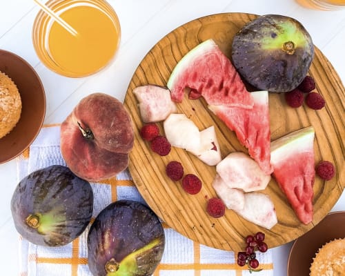Higos frescos, sandía y frambuesas en tabla de madera del desayuno de Casa Rural Villa del Jerte