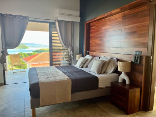 Chambre de la villa Passion Vanille avec tête de lit en bois, balcon vue mer, Les Trois-Ilets, Martinique