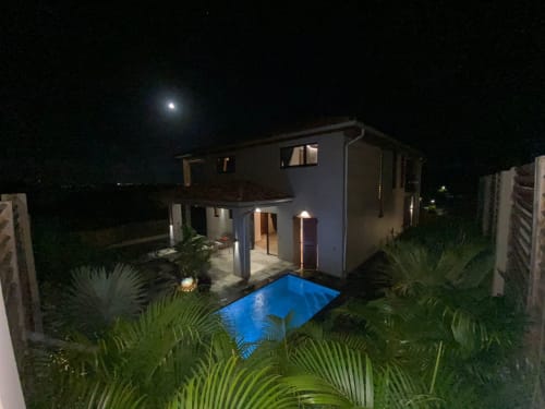 Villa Passion Vanille illuminée de nuit avec piscine privée, jardin tropical et ciel étoilé aux Trois-Ilets