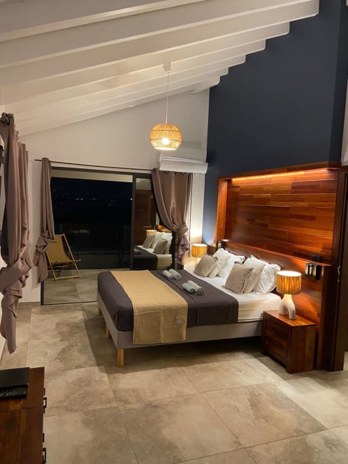 Chambre luxueuse à Les Trois-Ilets avec vue mer, tête de lit en bois, mobilier moderne et accès au balcon