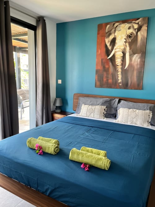 Chambre moderne de la villa Les Hébergements Passion en Martinique avec murs turquoise, literie bleue et décoration éléphanteau