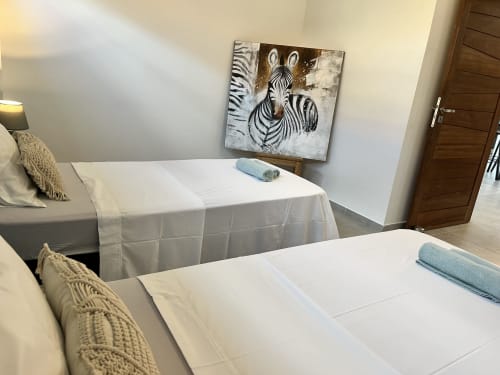 Chambre moderne de la villa Les Hébergements Passion avec lits jumeaux, œuvre zèbre et serviettes bleues en Martinique