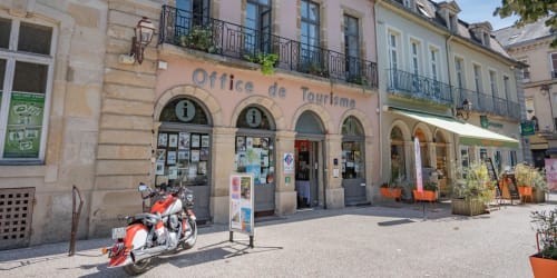Fremdenverkehrsbüro in Epinac, Frankreich mit rotem Motorrad vor historischen Steingebäuden