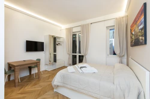 Modernes Schlafzimmer in den Magnolia Apartments Mailand mit Bett, Schreibtisch, TV, Spiegelschrank und Parkettboden