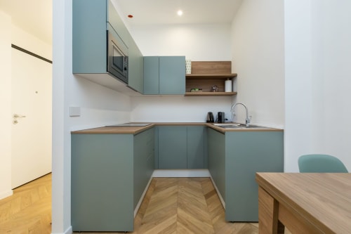 Moderne Küche in Magnolia Apartments Mailand mit Salbeigrünen Schränken, Holzarbeitsplatten und Essbereich mit Parkettboden