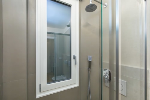 Modernes Badezimmer mit Regenduschkopf, Glastrennwand und weißen Fliesen in Magnolia Apartments Milan