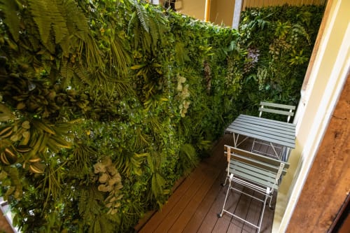 Üppige grüne Wand mit tropischen Pflanzen auf dem Balkon eines Mailänder Apartments mit modernem Mobiliar und Holzboden