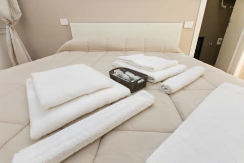 Ordentlich angeordnete weiße Handtücher und Toilettenartikel auf dem Bett im Hotelzimmer Magnolia Apartments Mailand