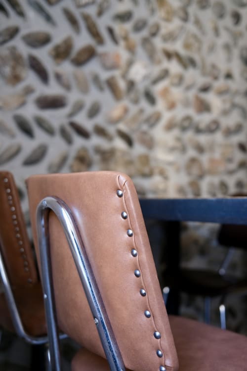 Moderner brauner Lederstuhl mit Nieten im Bergamo City Center Apartment, Metallrahmen und gemusterter Wandhintergrund