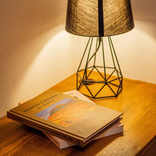 Acogedor rincón de lectura en Casa Sofi Oaxaca con lámpara y literatura en español sobre mesa de madera