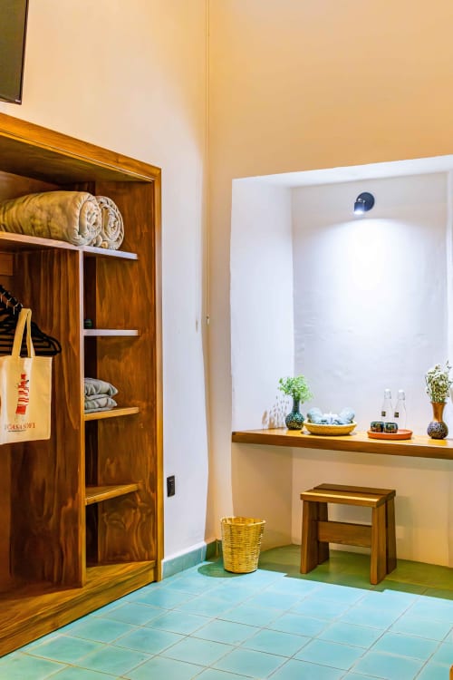 Dormitorio Casa Sofi Oaxaca con estantes de madera, piso de azulejos turquesas y amenidades spa