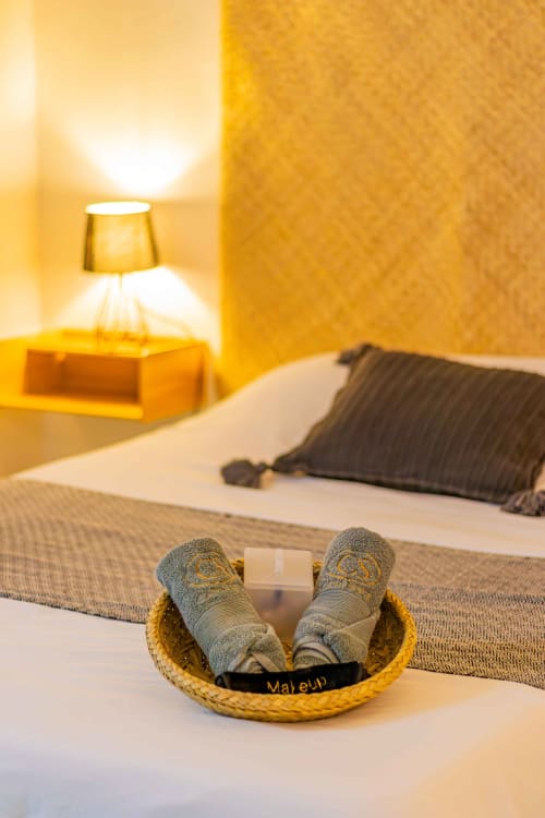 Acogedora habitación en Casa Sofi Oaxaca con pantuflas, lámpara y almohadas en tonos dorados cálidos