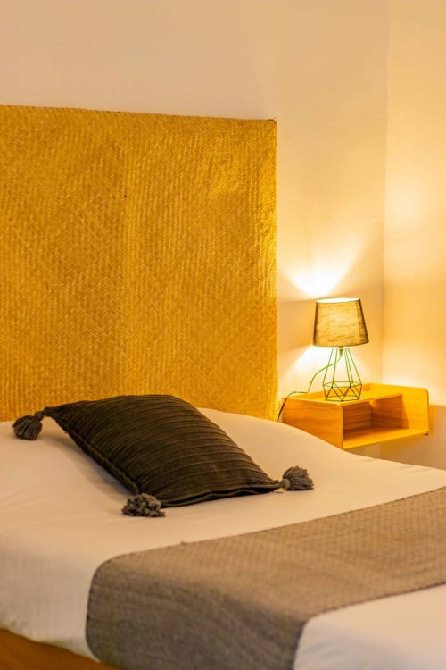 Acogedora habitación en Casa Sofi Oaxaca con cabecera amarillo mostaza, almohada oscura e iluminación ambiental