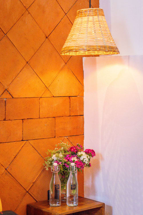 Rincón luminoso en Casa Sofí Oaxaca con azulejos de barro, lámpara tejida, flores en botellas de vidrio y pared blanca