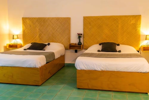 Luminosa habitación doble en Casa Sofi Oaxaca con cabeceras amarillas, ropa de cama blanca y piso de azulejos turquesas