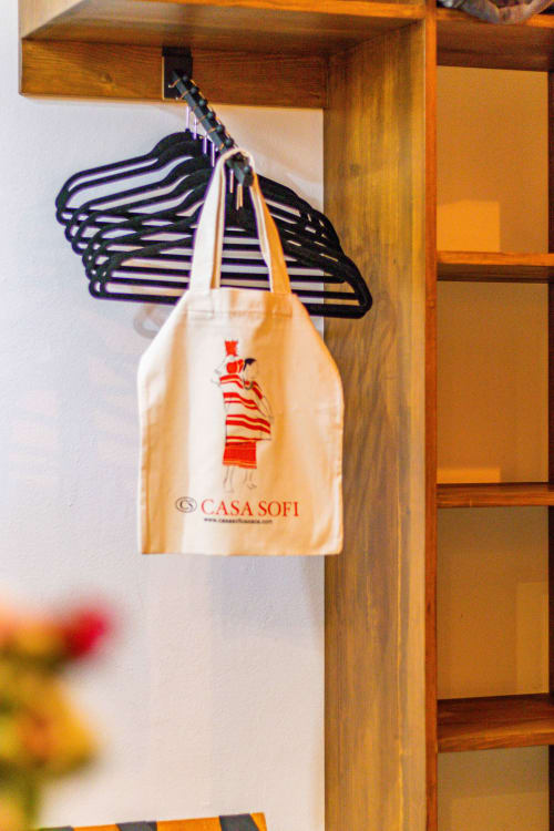 Bolsa de Casa Sofi Oaxaca colgada en barra de madera del closet con perchas negras en habitación de huéspedes