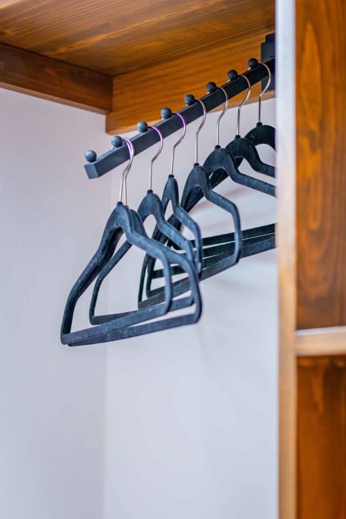 Perchas de madera negra en barra del closet de la habitación de Casa Sofi Oaxaca con paredes blancas